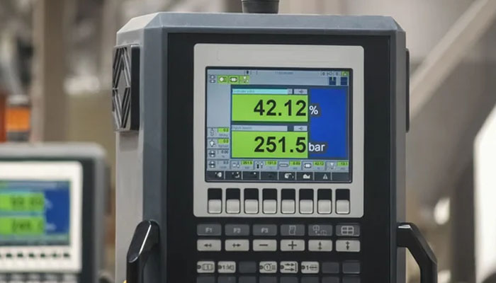 Close-up of an industrial digital pressure controller displaying 42.12% and 251.5 bar on a color screen with multiple control buttons.